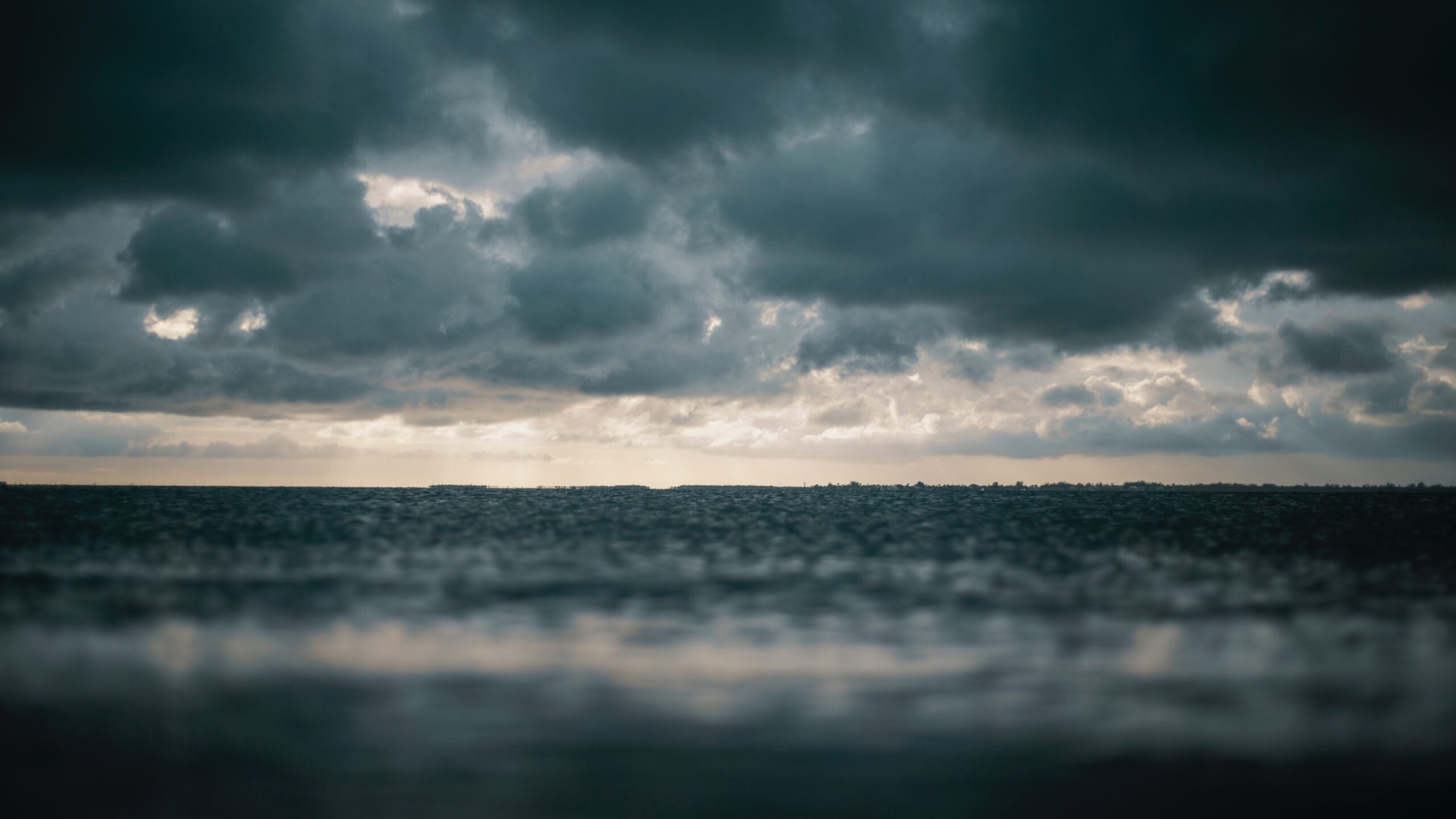 Dark blue clouds and ground meet at the dim horizon symbolizing the unforgiving and unpredictable nature of endometriosis